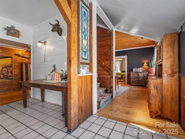 hallway featuring wooden walls and light tile patterned floors