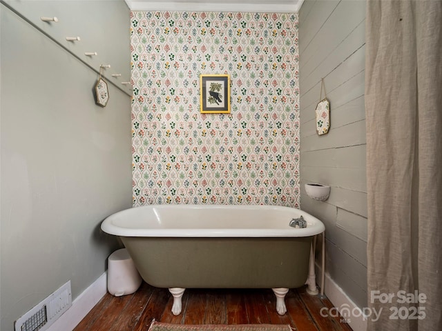 bathroom featuring ornamental molding, a tub to relax in, and hardwood / wood-style flooring