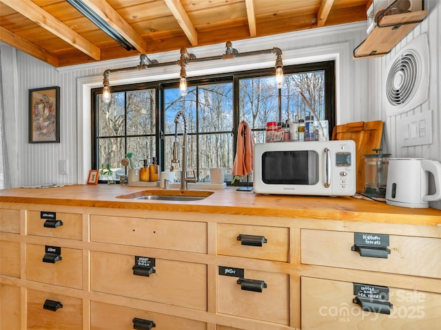 kitchen with beam ceiling, wooden ceiling, butcher block countertops, and sink