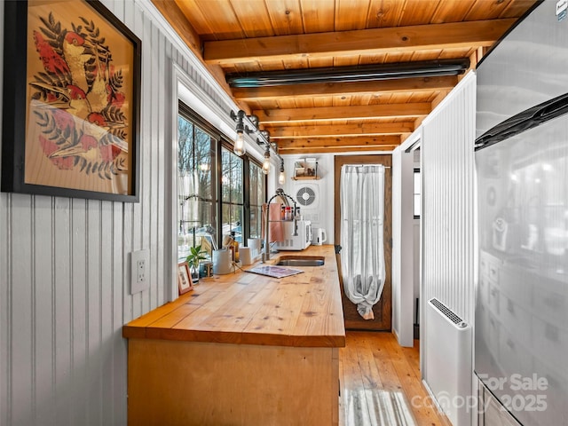 kitchen featuring sink, wooden ceiling, wooden walls, and beamed ceiling