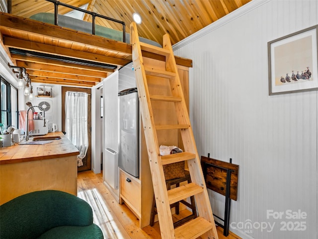 kitchen featuring sink, light hardwood / wood-style flooring, ornamental molding, and wooden ceiling