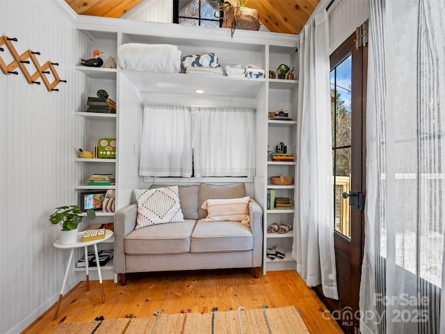 living area featuring wooden walls, wood ceiling, and light hardwood / wood-style flooring