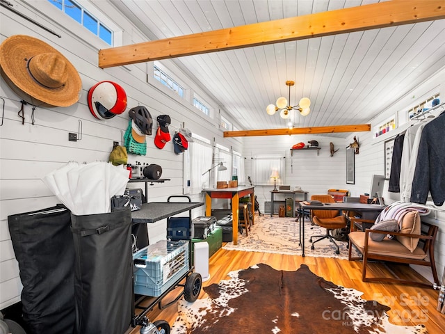 misc room featuring a notable chandelier, wooden walls, beamed ceiling, and wood-type flooring