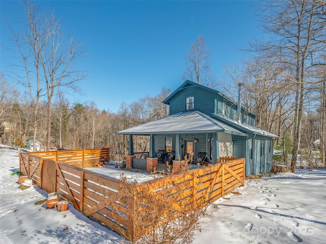 snow covered back of property with covered porch