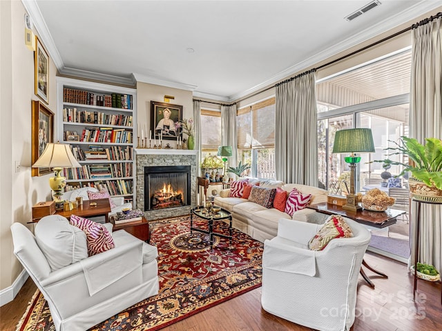 living room with hardwood / wood-style floors, ornamental molding, and a fireplace