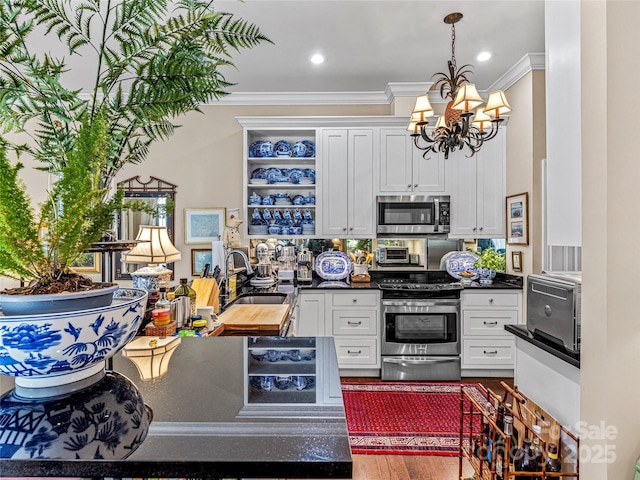 kitchen featuring sink, crown molding, an inviting chandelier, white cabinetry, and appliances with stainless steel finishes