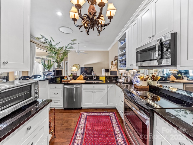 kitchen with appliances with stainless steel finishes, dark hardwood / wood-style floors, ornamental molding, ceiling fan with notable chandelier, and white cabinets