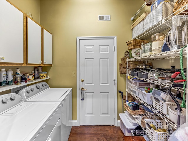 clothes washing area with dark hardwood / wood-style floors, washer and dryer, and cabinets