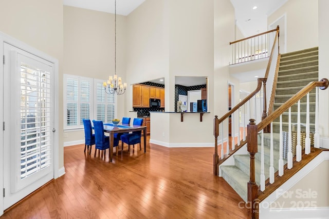 dining space with a chandelier, light hardwood / wood-style flooring, and a high ceiling