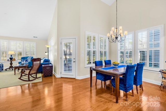 dining room featuring hardwood / wood-style floors, high vaulted ceiling, a notable chandelier, and a wealth of natural light