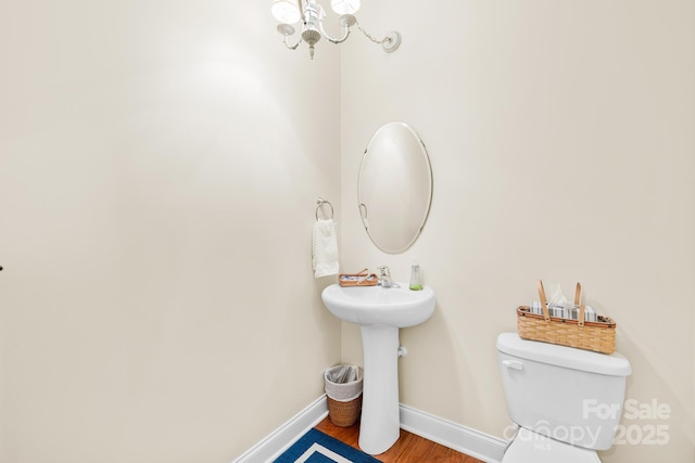 bathroom featuring wood-type flooring, a chandelier, and toilet