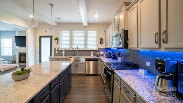 kitchen featuring pendant lighting, backsplash, light stone countertops, appliances with stainless steel finishes, and beamed ceiling