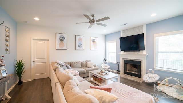 living room featuring dark hardwood / wood-style flooring, a large fireplace, and ceiling fan