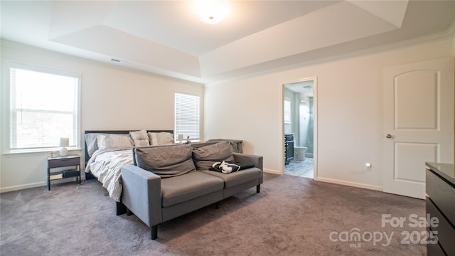 bedroom featuring a tray ceiling, ensuite bath, dark carpet, and ornamental molding