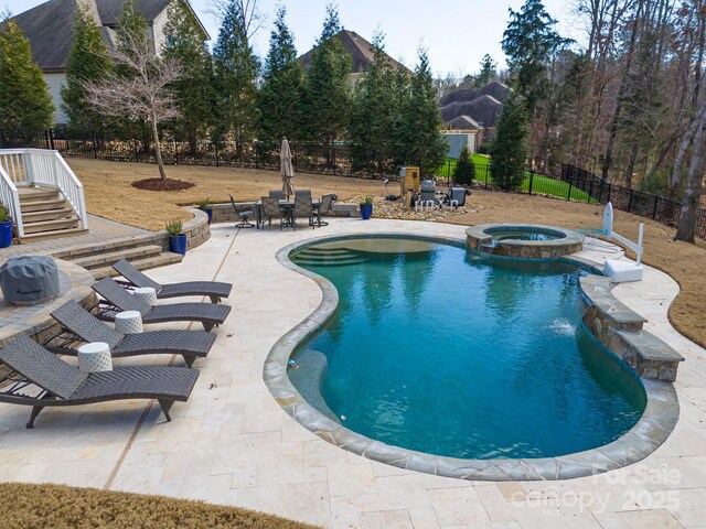 view of swimming pool featuring a pool with connected hot tub, a patio area, and fence