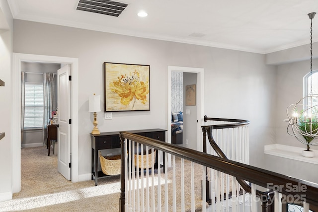 hall featuring baseboards, visible vents, light colored carpet, crown molding, and an upstairs landing