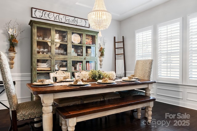 dining area featuring wainscoting, dark wood-type flooring, plenty of natural light, and a notable chandelier