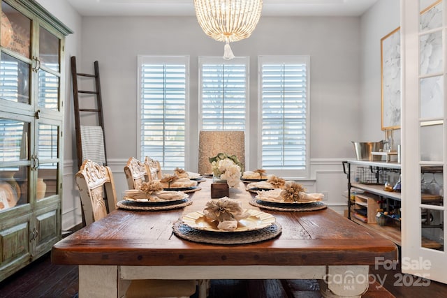 dining room featuring a wainscoted wall, a decorative wall, dark wood finished floors, and a chandelier