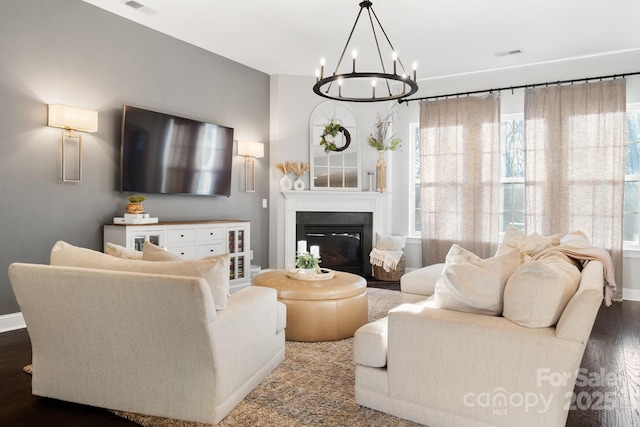 living area with visible vents, baseboards, dark wood-style flooring, and a glass covered fireplace