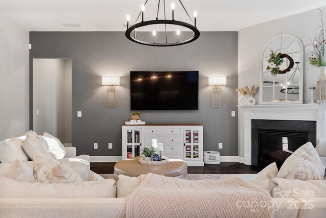 living area with a fireplace with flush hearth, baseboards, a chandelier, and wood finished floors