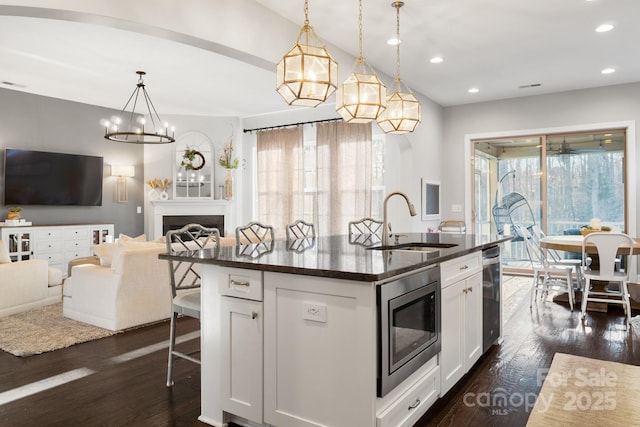 kitchen with dark wood-style flooring, a fireplace, stainless steel microwave, open floor plan, and a sink