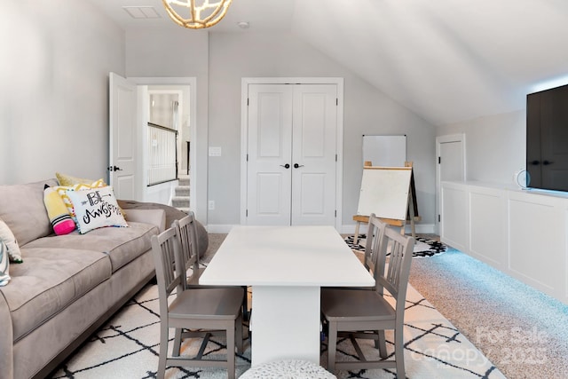 dining space featuring vaulted ceiling, stairs, and light colored carpet