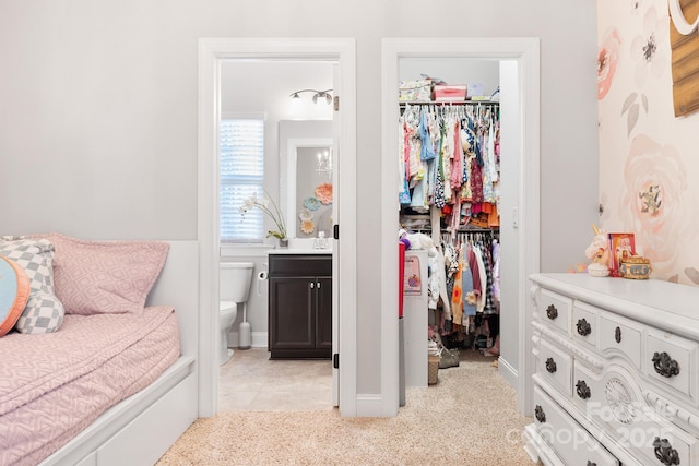 bedroom with light carpet, ensuite bath, a closet, and a walk in closet