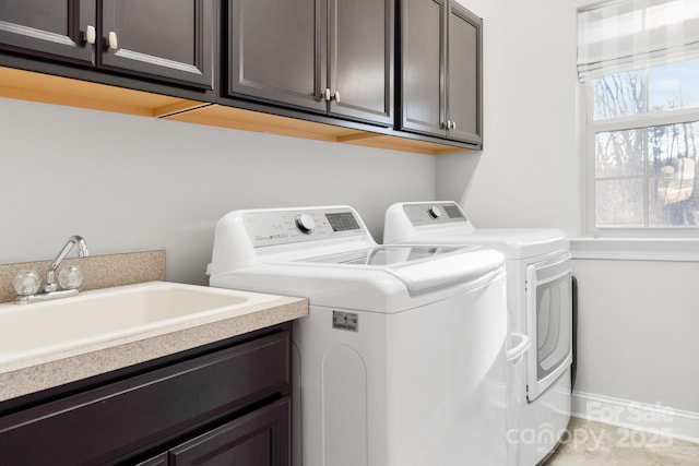 washroom with washer and dryer, cabinet space, a sink, and baseboards