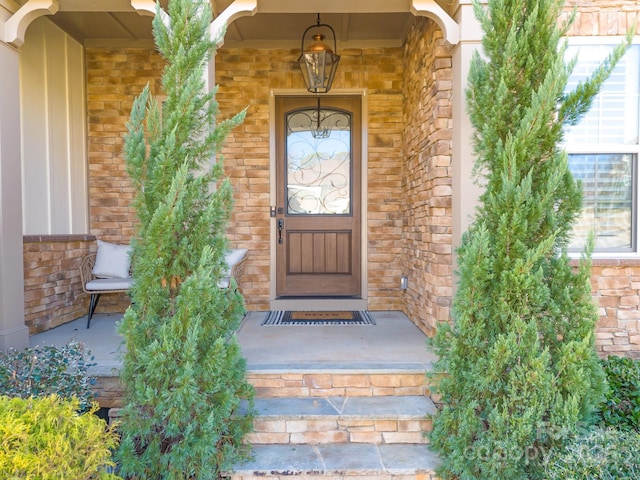 doorway to property with stone siding, a porch, and brick siding