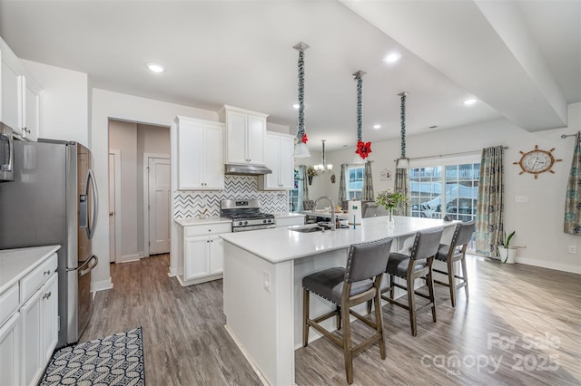 kitchen featuring sink, a breakfast bar area, stainless steel appliances, a kitchen island with sink, and white cabinets