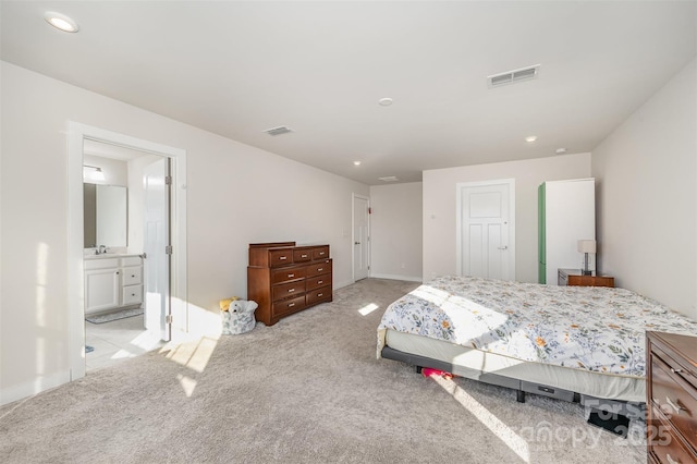 bedroom with sink, ensuite bath, light colored carpet, and a closet