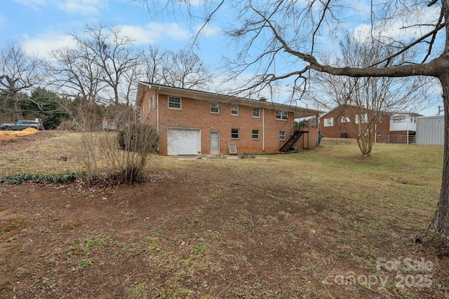 rear view of property with a garage and a lawn