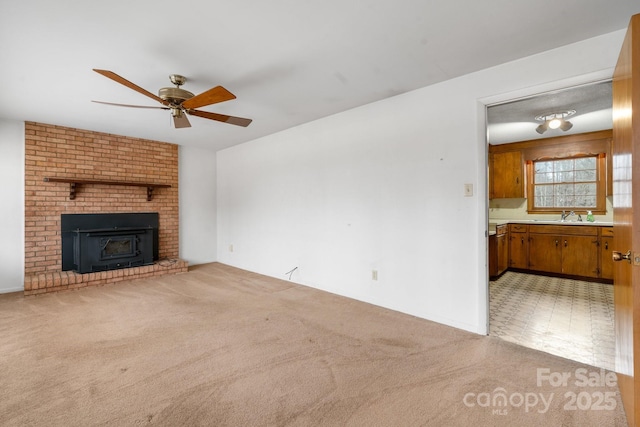 unfurnished living room with sink, light carpet, a fireplace, and ceiling fan