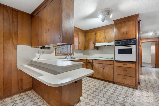 kitchen with white appliances, wooden walls, kitchen peninsula, and sink