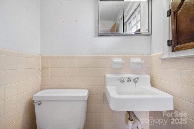 bathroom featuring tile walls, sink, and toilet