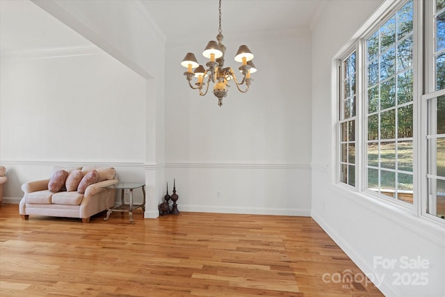 living area featuring light wood-type flooring, crown molding, and a chandelier