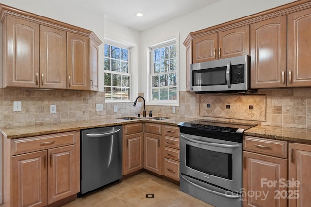 kitchen with backsplash, sink, light stone countertops, appliances with stainless steel finishes, and light tile patterned floors