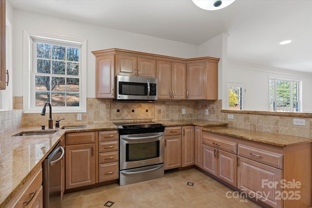 kitchen featuring appliances with stainless steel finishes, sink, backsplash, light tile patterned flooring, and light stone counters