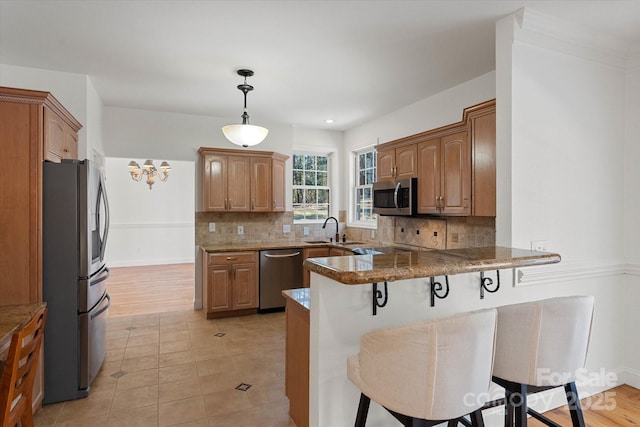 kitchen with a breakfast bar, kitchen peninsula, backsplash, and stainless steel appliances