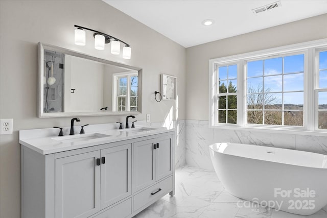 bathroom with tile walls, a tub to relax in, and vanity