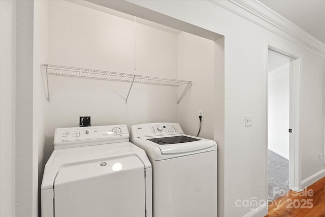 clothes washing area with crown molding, separate washer and dryer, and hardwood / wood-style floors