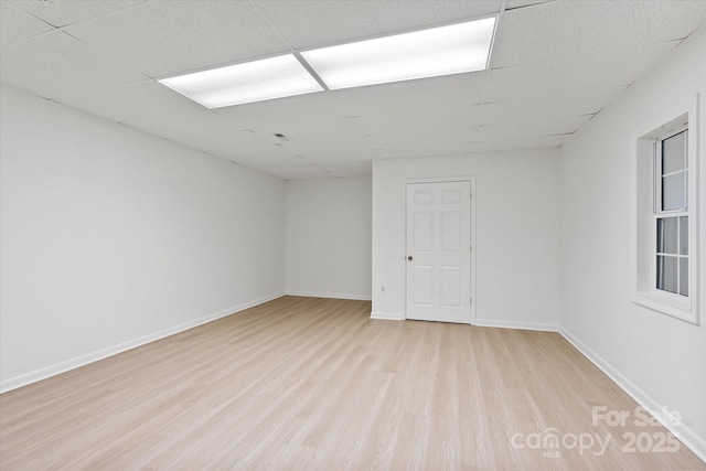 empty room featuring a paneled ceiling and light hardwood / wood-style flooring