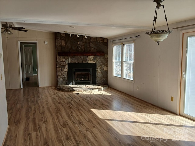 unfurnished living room featuring wood-type flooring and a stone fireplace