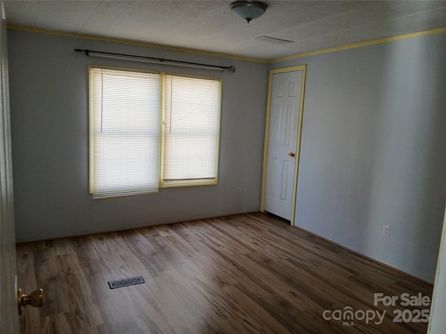 unfurnished room with ornamental molding and hardwood / wood-style floors