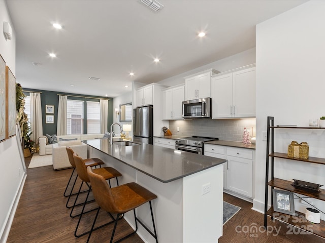 kitchen featuring sink, a breakfast bar area, an island with sink, white cabinetry, and stainless steel appliances