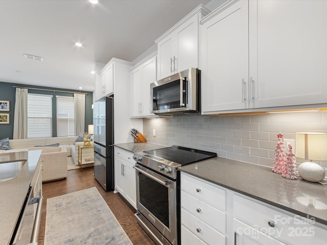 kitchen featuring dark wood-type flooring, sink, decorative backsplash, appliances with stainless steel finishes, and white cabinetry