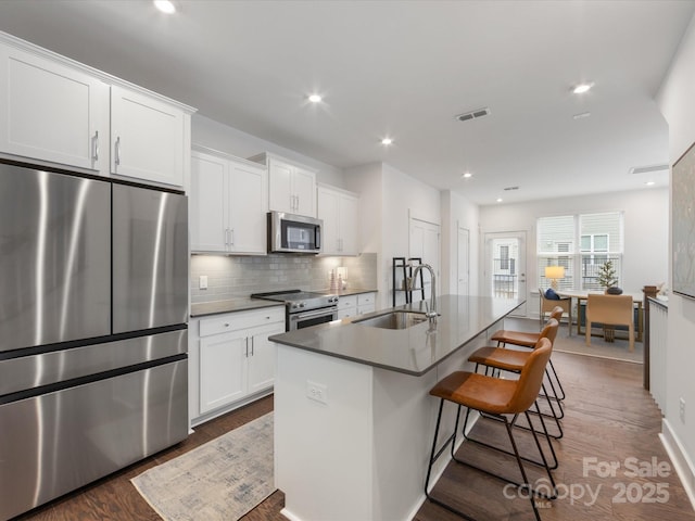 kitchen featuring a breakfast bar, white cabinets, sink, an island with sink, and stainless steel appliances