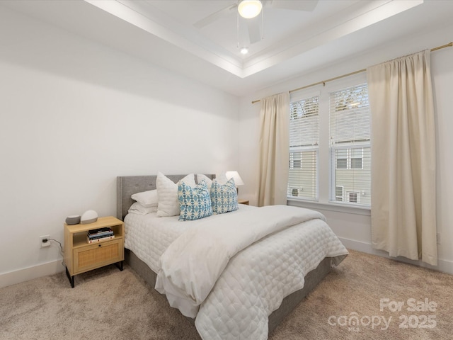 bedroom with carpet, ceiling fan, multiple windows, and a tray ceiling