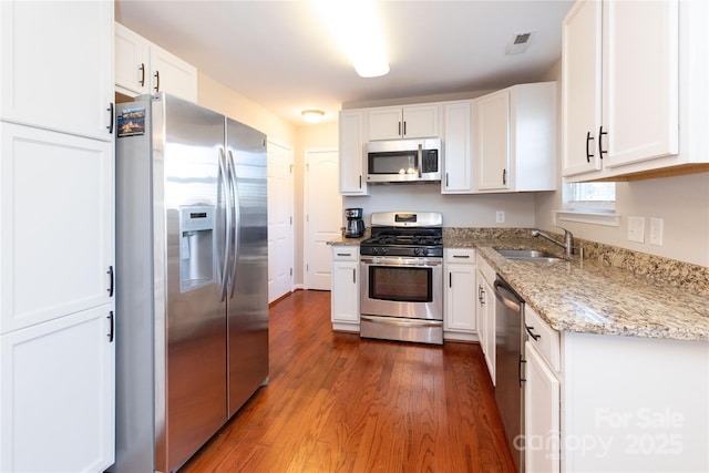 kitchen with sink, white cabinetry, dark wood-type flooring, light stone countertops, and appliances with stainless steel finishes