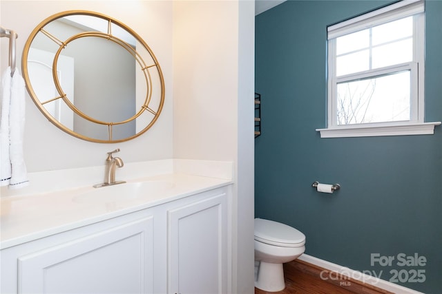 bathroom with toilet, hardwood / wood-style floors, and vanity